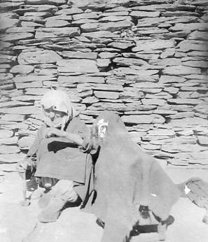 Пожилая женщина с веретеном у детской люльки в ауле Хуландой.